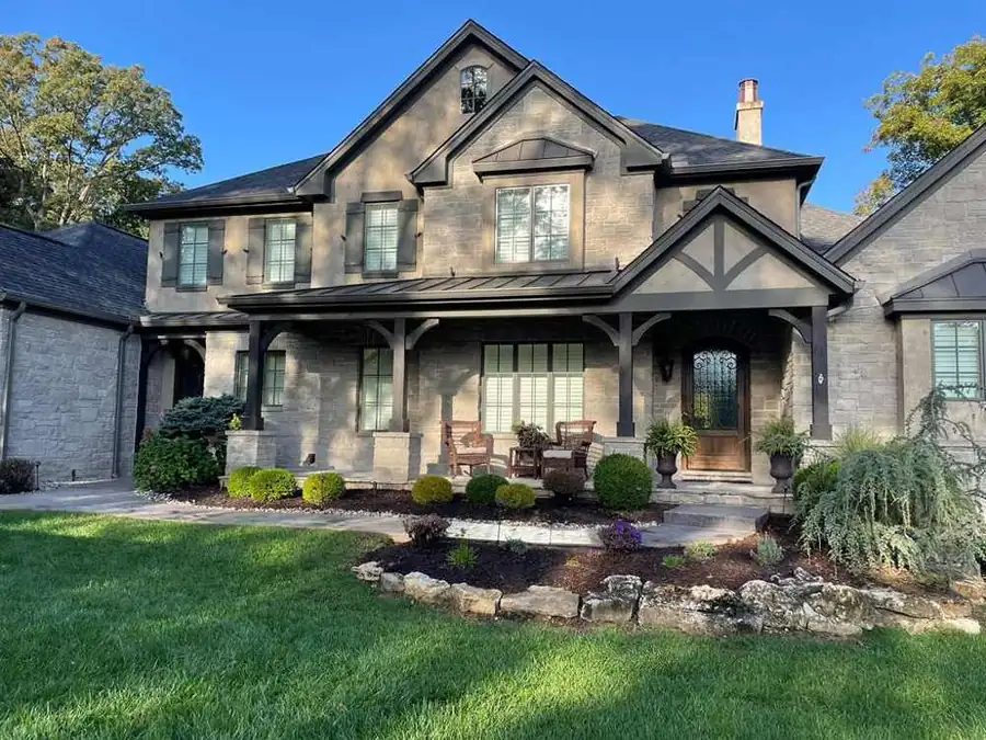 Stone home with new seamless gutters, covered porch and landscaped front yard