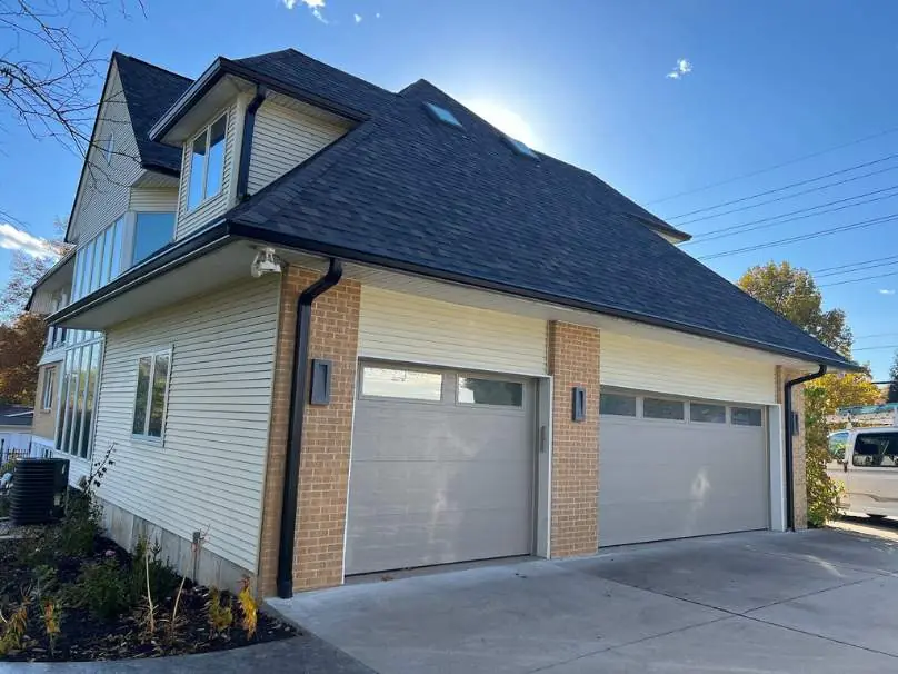 Home with new seamless gutters and downspouts on the brick corners of the garage
